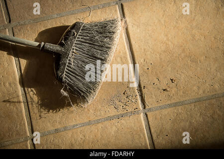 Alte Besen auf Fliesenboden mit Schmutz Haufen Stockfoto