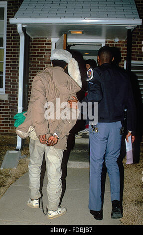 Langley Park, Maryland, USA, hatte 1988 Prinz Georges County Maryland Polizisten mithilfe ein Hundes sie begreifen, dass dies Crack-Kokain-Händler vermutet, die auf die Oberseite eines Autos versuchen, Weg von den Offizieren gelaufen war. Der Eckzahn Handler schickte den Hund auf das Auto, den Verdächtigen auf wo sie den Verdächtigen Handschellen und vervollständigen die Verhaftung zu ziehen. Hier geht ein Polizist der mutmaßlichen Drogendealer in der Polizeistation in Hyattsville MD.  Bildnachweis: Mark Reinstein Stockfoto