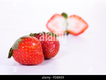 zwei ganze Erdbeeren im Vordergrund und eine gehackte in der Mitte von hinten Stockfoto