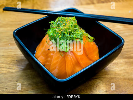 Tasse Lachs Sushi und grüne Algen an der Spitze Stockfoto