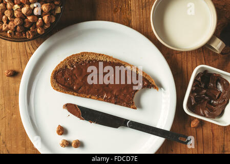 Haselnuss-Nougat-Creme bestreichen Brotscheibe, süße Köstlichkeit zum Abendessen. Stockfoto