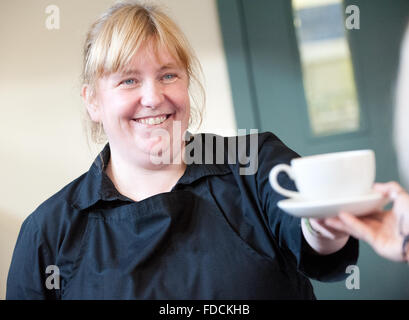 Kellnerin im Cafe Übergabe Kunde eine Tasse Tee. Stockfoto