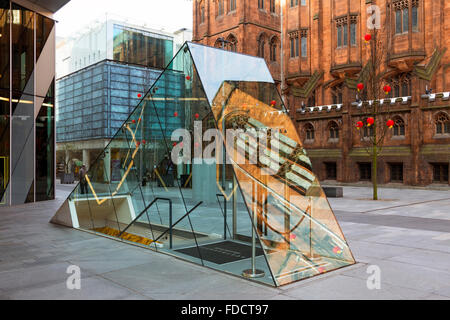 Der Glaseingang zum unterirdischen Australasia Restaurant, Spinningfields, Deansgate, Manchester, Großbritannien. John Rylands Bibliothek dahinter. Stockfoto