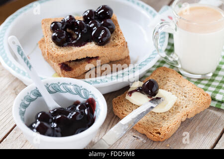 Frühstück mit Sauerkirschen Marmelade Milch und Zwieback Stockfoto