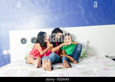 3 Personen Mutter und Kinder, Tochter und Sohn sitzen Schlafzimmer Spaß Stockfoto