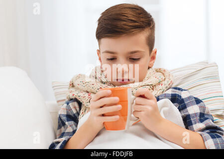 krank junge mit Grippe in Schal Teetrinken zu Hause Stockfoto