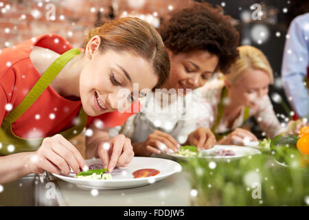 Glückliche Frauen kochen und dekorieren Gerichte Stockfoto