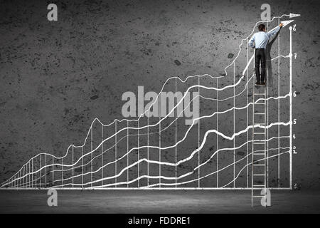 Back View-Bild der Geschäftsmann zeichnen von Grafiken auf Wand Stockfoto