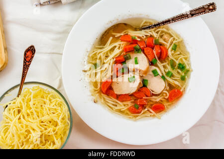 Traditionelle Hühnersuppe mit Fleisch und Karotten und Nudeln auf weißen Tisch Stockfoto