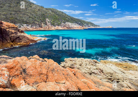 Sleepy Bay, Freycinet, Tasmanien, Australien mit blauer Himmel, klares Wasser und orangefarbenen Flechten bedeckt Felsen Stockfoto