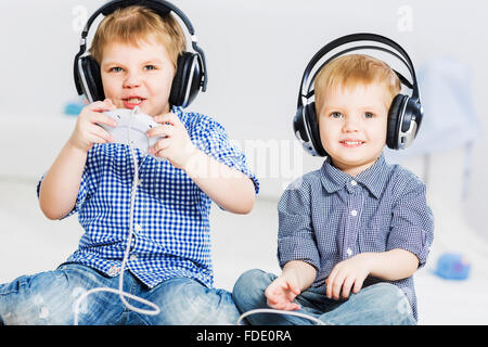 Süße Jungs spielen in Funkkopfhörer Stockfoto