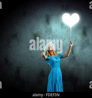 Junge hübsche Frau im blauen Hut und Kleid mit Ballon Stockfoto