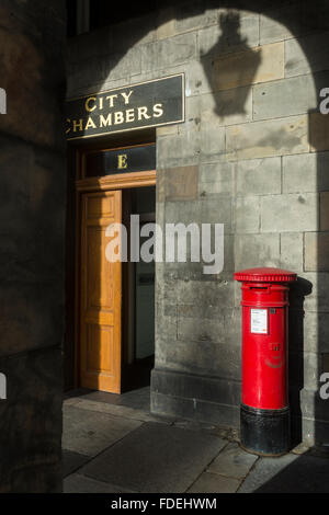 Sonnenlicht scheint auf den Eingang der Stadt Kammern in Edinburgh wirft einen Schatten von der reich verzierten Straßenlaterne an der Wand Stockfoto