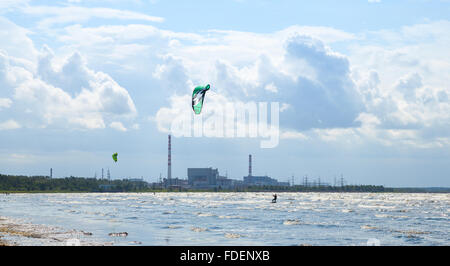 Sosnovy Bor, Russland - 19. Juli 2015: Kitesurfer reiten die Wellen der finnischen Meerbusen mit dem Kernkraftwerk Leningrad Stockfoto