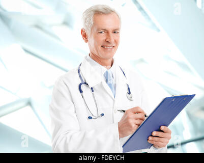 Porträt von glücklich Reife Arzt schreiben das Ergebnis der medizinischen Test beim stehen in Klinik. Stockfoto
