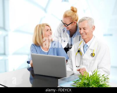 Porträt der drei Ärzte arbeiten am Laptop, beim Sitzen am Schreibtisch in Privatklinik. Stockfoto