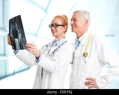 Ärztin hält Röntgenbild und Rücksprache mit männlichen Arzt im Krankenhaus. Stockfoto