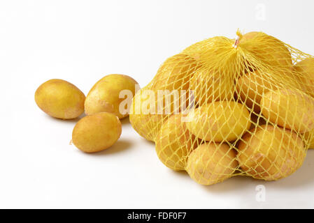 Babykartoffeln im netting-Sack auf weißem Hintergrund Stockfoto