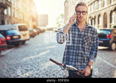 Ein Porträt von ein hübscher junger Mann reden auf seinem Handy in der Stadt Stockfoto