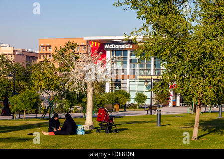 Zwei Frauen sitzen im Chat In einem Park, Doha, Katar Stockfoto