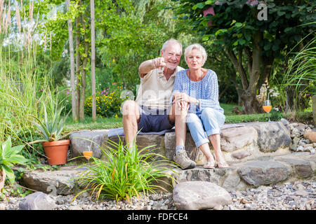 gerne älteres Paar im Garten Lächeln und Lachen in der Sonne genießen Ruhestand Stockfoto