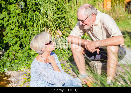 gerne älteres Paar im Garten Lächeln und Lachen in der Sonne genießen Ruhestand Stockfoto