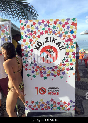 Rio De Janeiro, Brasilien. 31. Januar 2016. Eine Frau steht neben einem Plakat an einem Stand der Stadtverwaltung auf Maßnahmen zum Schutz vor gefährlichen Zika-Virus, an einem Strand im Stadtteil Ipanema von Rio De Janeiro, Brasilien, 31. Januar 2016. Flyer mitverteilt, enthält den Schriftzug "Xo, Zika" (Buzz off Zika) und einer durchgestrichenen Mücke, unter Bezugnahme auf die Virus-übertragende Mücke Arten Gelbfiebermücke. Bildnachweis: Dpa picture Alliance/Alamy Live News Stockfoto