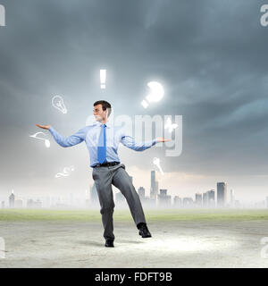 Junger Geschäftsmann Jonglieren mit konzeptionellen Symbole Hintergrund Stadt Stockfoto