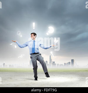 Junger Geschäftsmann Jonglieren mit konzeptionellen Symbole Hintergrund Stadt Stockfoto