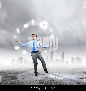 Junger Geschäftsmann Jonglieren mit konzeptionellen Symbole Hintergrund Stadt Stockfoto