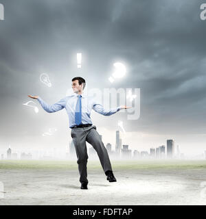 Junger Geschäftsmann Jonglieren mit konzeptionellen Symbole Hintergrund Stadt Stockfoto