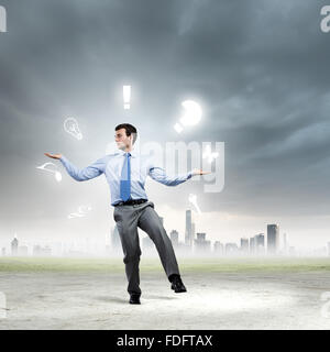 Junger Geschäftsmann Jonglieren mit konzeptionellen Symbole Hintergrund Stadt Stockfoto