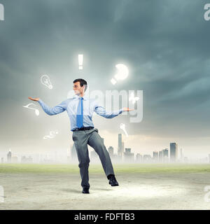 Junger Geschäftsmann Jonglieren mit konzeptionellen Symbole Hintergrund Stadt Stockfoto
