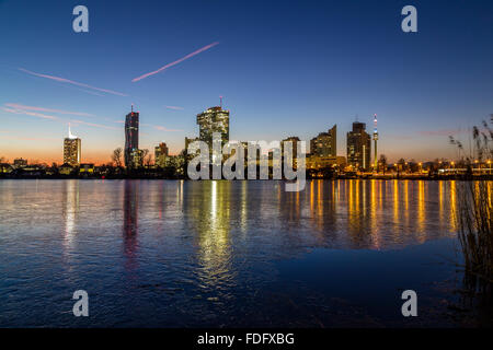 Ein Blick auf Gebäude in der Nähe der alten Donau in Wien. Im Winter bei Sonnenuntergang aufgenommen. Gefrorenen Eis auf dem See zu sehen. Stockfoto