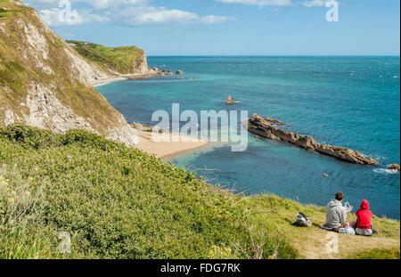 Wanderer mit Blick auf die St. Oswald Bay an der "Durdle Door" Cliff-Bildung in der Nähe von Lulworth, Dorset, Südengland. Stockfoto