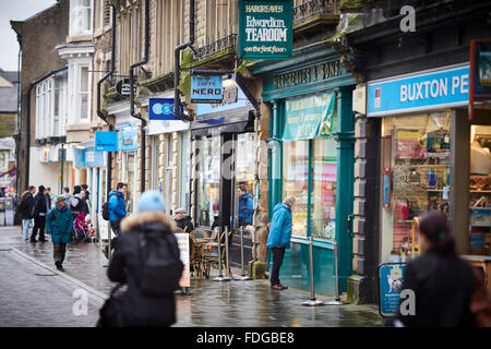 Buxton Main shopping street Spring Gardens, eine Mischung aus unabhängig und Kette Geschäfte Wetter nass regnen feuchten Winter trüber Tag beschäftigt st Stockfoto