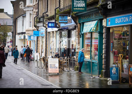 Buxton Main shopping street Spring Gardens, eine Mischung aus unabhängig und Kette Geschäfte Wetter nass regnen feuchten Winter trüber Tag beschäftigt st Stockfoto