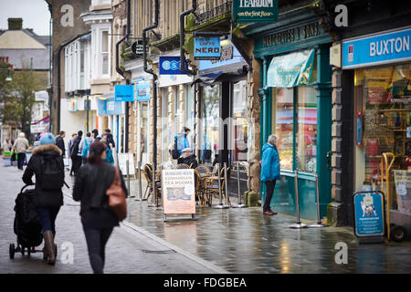 Buxton Main shopping street Spring Gardens, eine Mischung aus unabhängig und Kette Geschäfte Wetter nass regnen feuchten Winter trüber Tag beschäftigt st Stockfoto