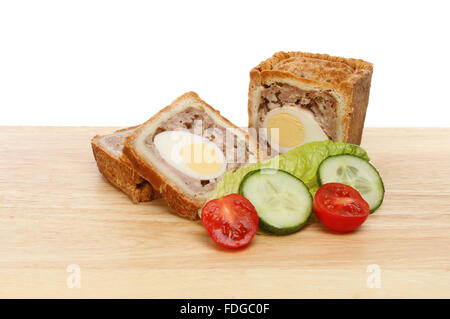 Scheiben von Schweine- und Ei Pie mit Salat auf einem Holzbrett vor einem weißen Hintergrund Stockfoto