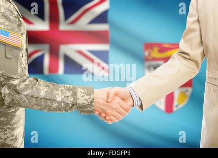 Amerikanische Soldaten in uniform und Zivil Mann im Anzug Händeschütteln mit Nationalflagge auf Hintergrund - Fidschi Stockfoto