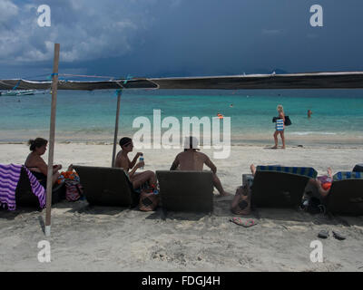 Touristen und traditionelle Boote am Strand von Gili Air Insel Lombok, Indonesien Stockfoto