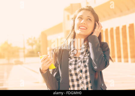 eine Mädchen hört Musik auf der Straße von ihrem smartphone Stockfoto