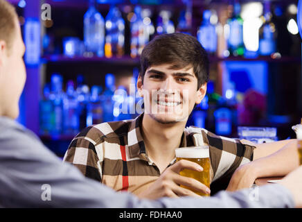 Zwei junge Männer sitzen an Bar und reden Stockfoto
