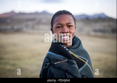 Porträt eines jungen Mannes in eine Decke gehüllt, mit Bergen im Hintergrund in Sani Pass, Lesotho, Afrika. Stockfoto