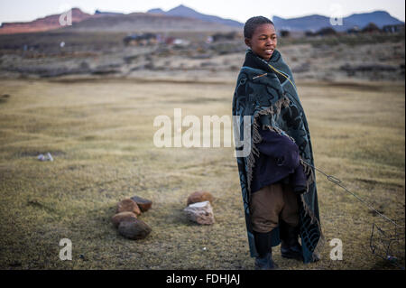 Porträt eines jungen Mannes in eine Decke gehüllt, mit Bergen im Hintergrund in Sani Pass, Lesotho, Afrika. Stockfoto