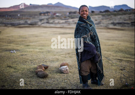 Porträt eines jungen Mannes in eine Decke gehüllt, mit Bergen im Hintergrund in Sani Pass, Lesotho, Afrika. Stockfoto