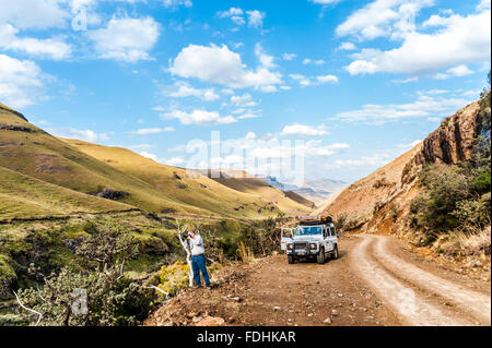 Land Rover Defender auf einer unbefestigten Straße geparkt und ein Mann fotografiert die Landschaft in Sani pass zwischen Südafrika und Lesotho Stockfoto