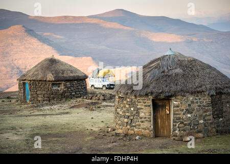 Land Rover geparkt mit einem Zelt hinter Hütten in einem Dorf in Lesotho, Afrika Stockfoto