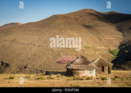 Zwei traditionelle Dorf Hütten vor einem Berg in Lesotho, Afrika Stockfoto