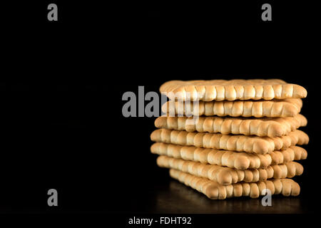 Stapel von knusprige Cracker vor schwarzem Hintergrund Stockfoto